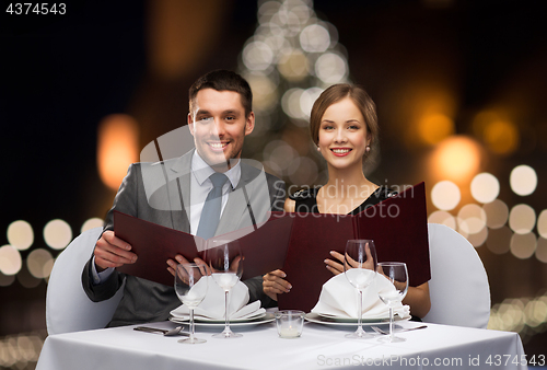 Image of smiling couple with menus at christmas restaurant