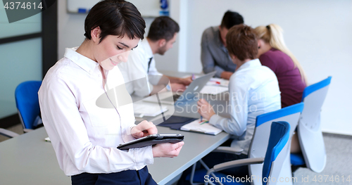 Image of Businesswoman using tablet with coworkers in backgorund having m