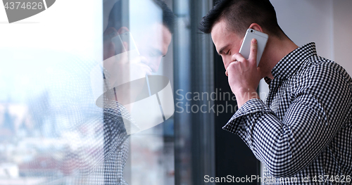 Image of Business Man Talking On Cell Phone, Looking Out Office Window