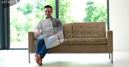 Image of Man is Laying on Couch at Home and Using Tablet