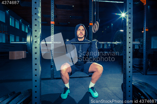 Image of Portrait of super fit muscular young man working out in gym with barbell