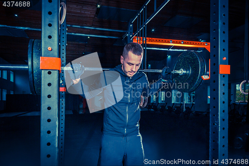 Image of Portrait of super fit muscular young man working out in gym with barbell