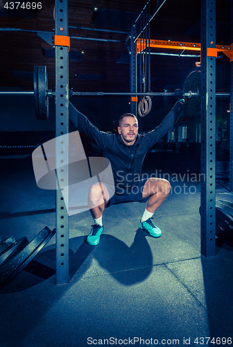 Image of Portrait of super fit muscular young man working out in gym with barbell