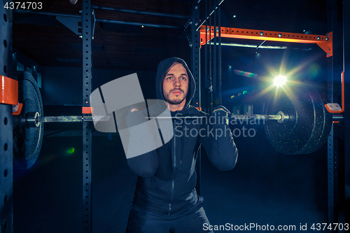 Image of Portrait of super fit muscular young man working out in gym with barbell