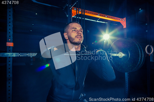 Image of Portrait of super fit muscular young man working out in gym with barbell