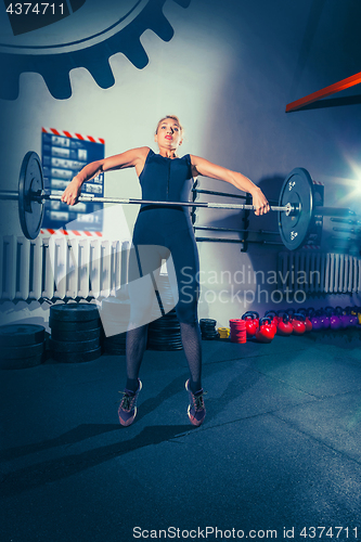 Image of Fit young woman lifting barbells working out in a gym