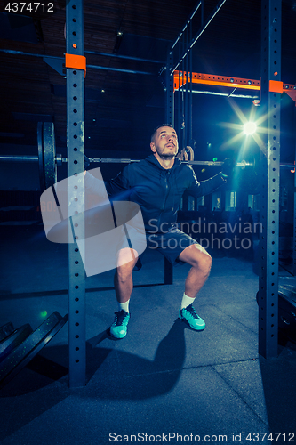 Image of Portrait of super fit muscular young man working out in gym with barbell