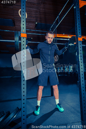 Image of Portrait of super fit muscular young man working out in gym with barbell