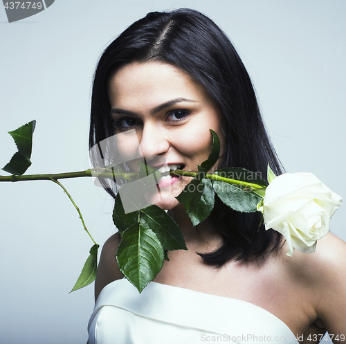 Image of young pretty brunette woman bride with white rose in her mouth, 