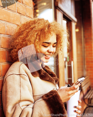 Image of young pretty african american women drinking coffee outside in c