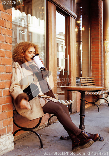 Image of young pretty african american women drinking coffee outside in c