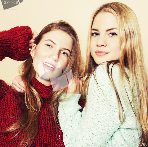 Image of Two young girlfriends in winter sweaters indoors having fun. Lif