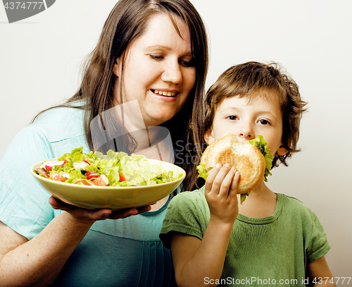 Image of mature woman holding salad and little cute boy with hamburger te