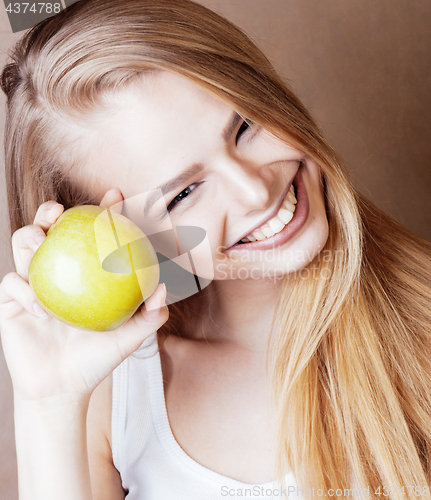 Image of young pretty blond woman with green apple happy cheerful smiling close up on warm brown background, lifestyle real people concept