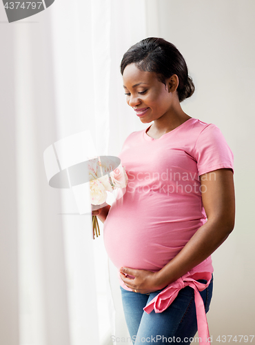 Image of happy african american pregnant woman with flowers