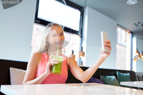 Image of woman with smartphone taking selfie at restaurant