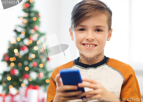 Image of close up of happy boy with smartphone at christmas