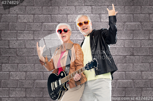 Image of senior couple with guitar showing rock hand sign