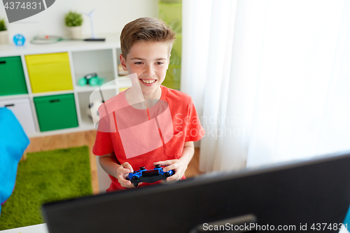 Image of boy with gamepad playing video game on computer