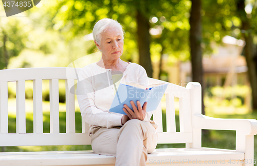 Image of senior woman reading book at summer park