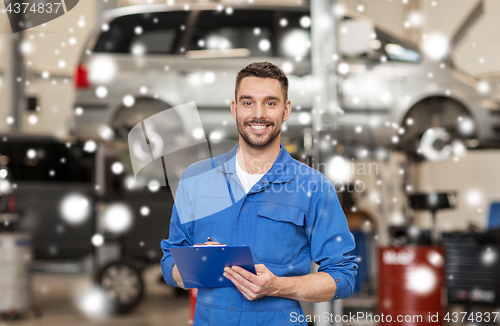 Image of happy mechanic man with clipboard at car workshop