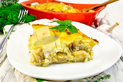 Image of Gratin potato with fish in plate on table