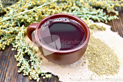 Image of Tea with wormwood in brown cup on dark board