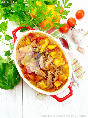 Image of Ragout of meat and vegetables in red brazier on board top