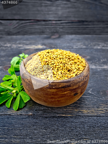 Image of Fenugreek with leaf in clay bowl on black wooden board