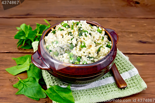 Image of Couscous with spinach and green peas in bowl on board