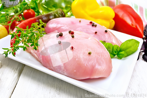 Image of Chicken breast raw in plate with vegetables on table