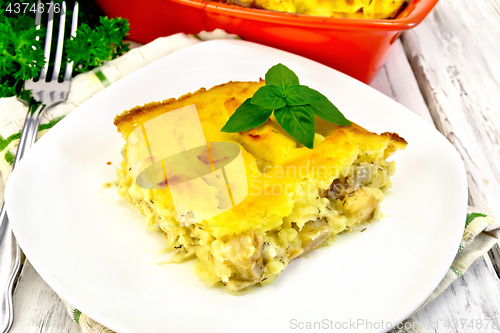 Image of Gratin potato with fish in plate on light board