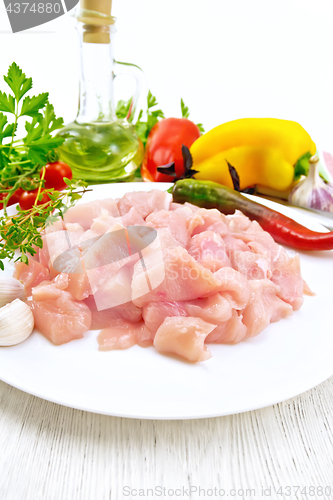 Image of Chicken breast raw sliced in plate with vegetables on board