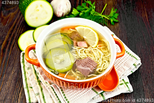 Image of Soup with zucchini and noodles in bowl on dark board