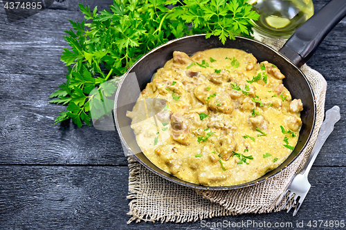 Image of Meat stewed with cream in pan on black board