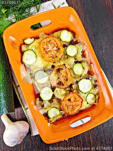 Image of Casserole from minced meat and zucchini in brazier on dark board