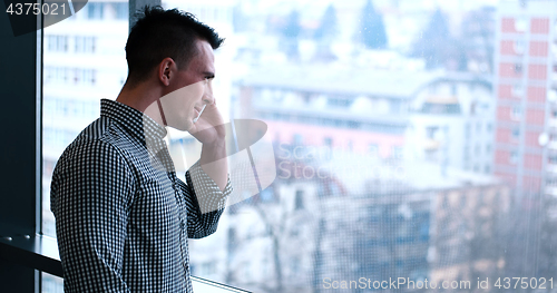 Image of Business Man Talking On Cell Phone, Looking Out Office Window