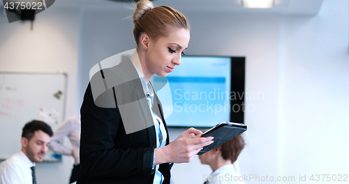 Image of Businesswoman using tablet with coworkers in backgorund having m