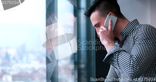 Image of Business Man Talking On Cell Phone, Looking Out Office Window