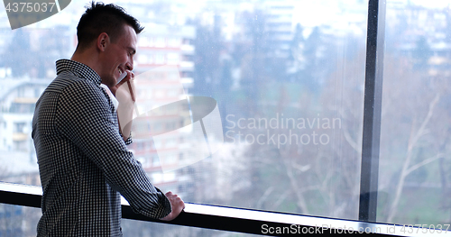 Image of Business Man Talking On Cell Phone, Looking Out Office Window