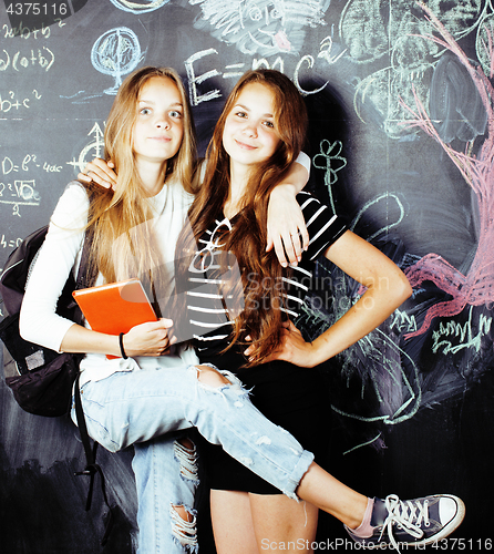 Image of back to school after summer vacations, two teen real girls in classroom with blackboard painted together, lifestyle people concept