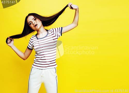 Image of young pretty teenage woman happy smiling posing on yellow background, fashion lifestyle people concept close up