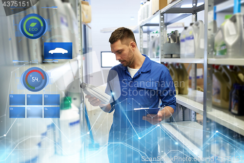 Image of auto mechanic with oil and clipboard at car shop