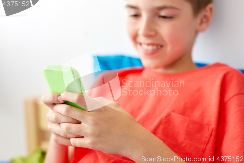 Image of close up of happy boy with smartphone at home