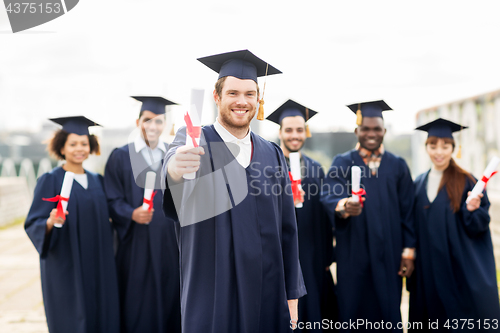 Image of happy students in mortar boards with diplomas