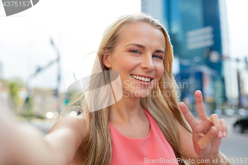 Image of happy young woman taking selfie on city street
