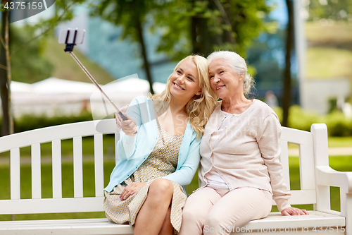 Image of daughter and senior mother taking selfie at park