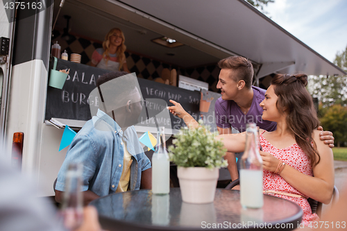 Image of friends with drinks sitting at table at food truck