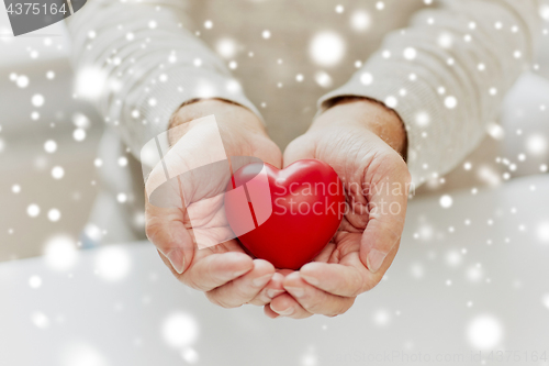 Image of close up of senior man with red heart in hands