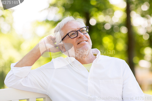 Image of happy senior man in glasses sitting at summer park